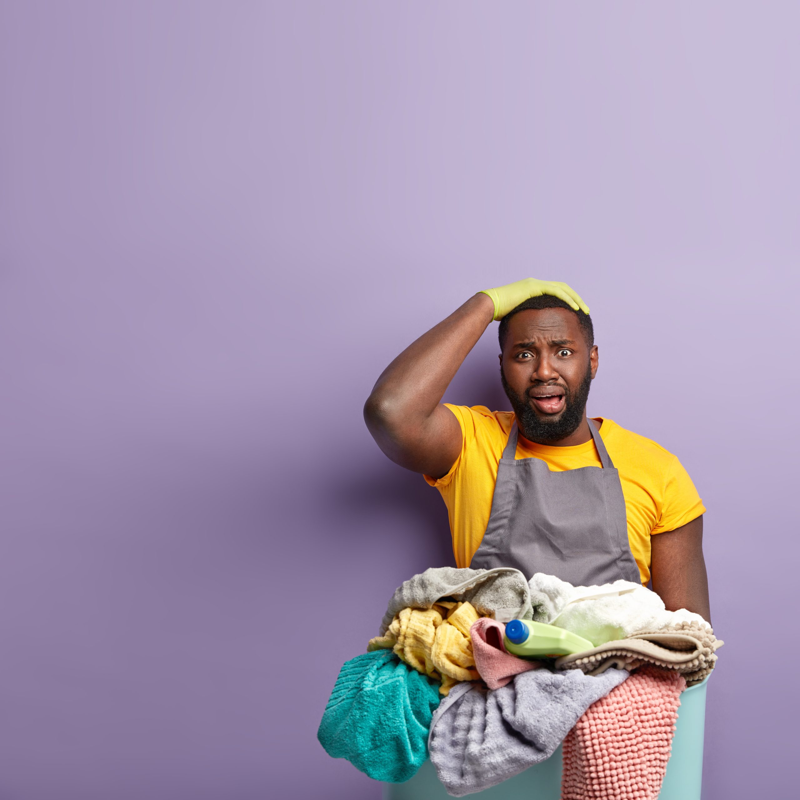 Emotional frustrated man keeps hand on head, dressed in casual clothes, overloaded with much work about house, expresses negative emotions, fed up of cleaning and washing, Housework concept.